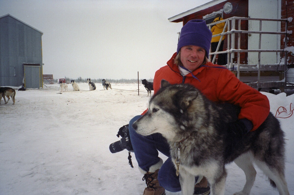 Person with husky in snowy outdoor setting.
