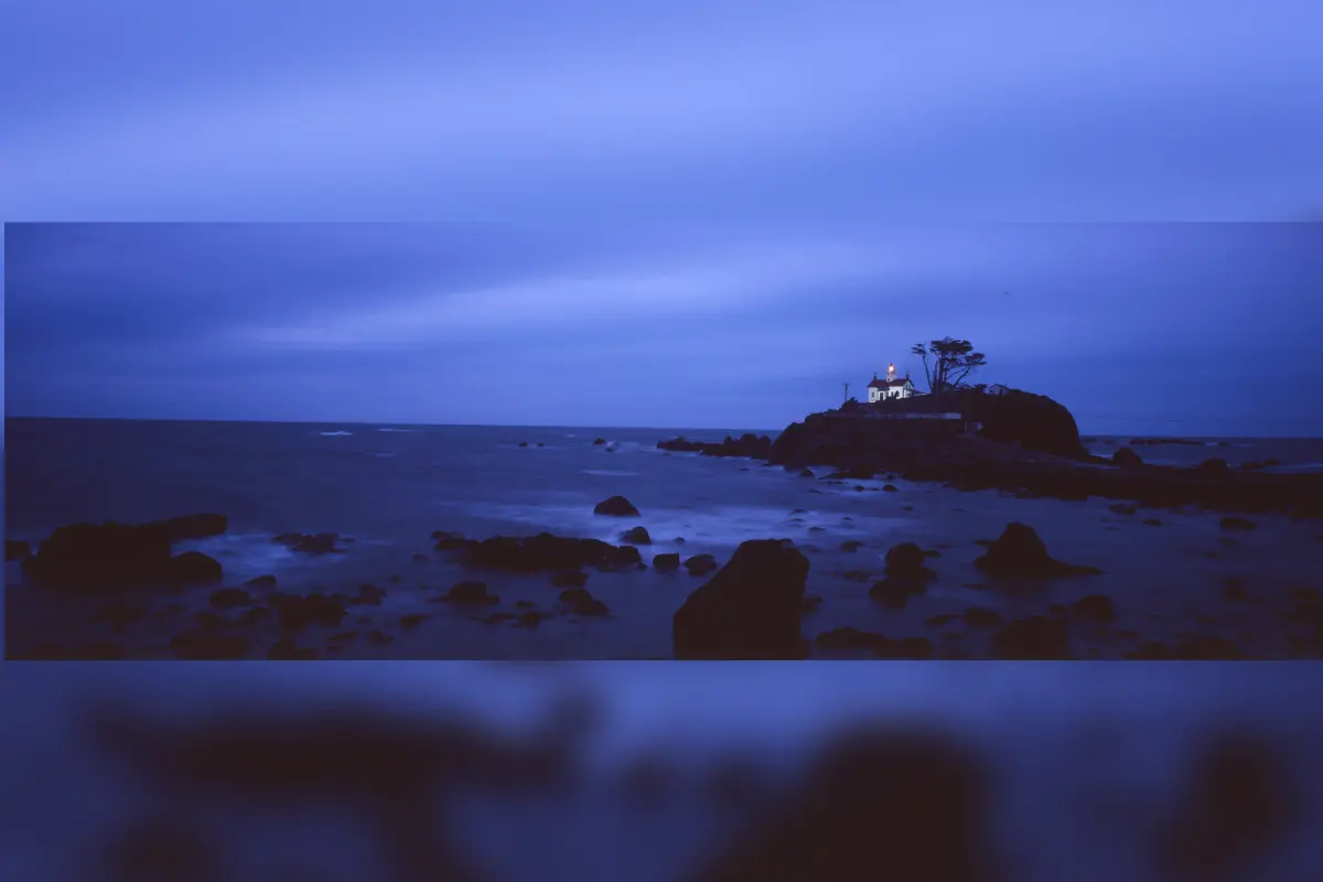 Lighthouse on rocky shore at twilight.